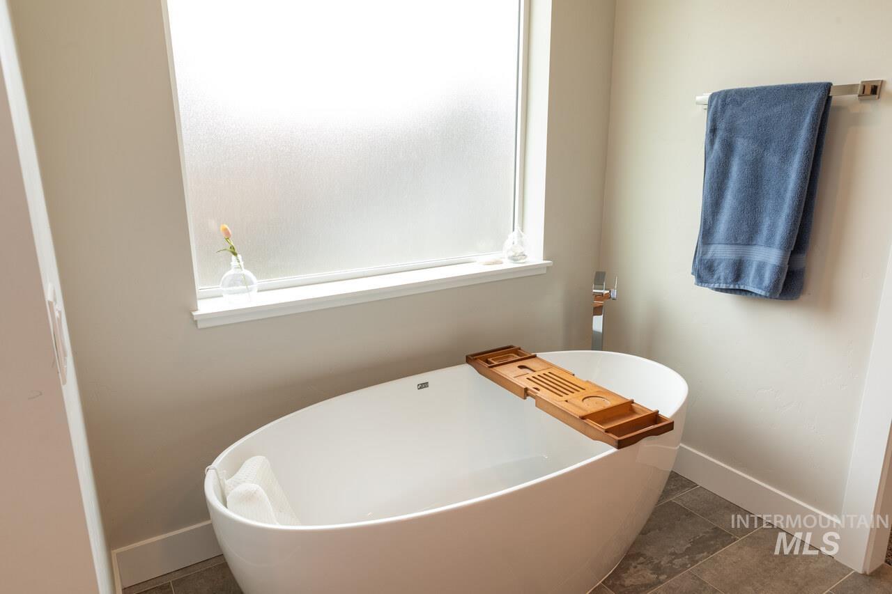 Full bathroom featuring a freestanding tub and dark tile patterned floors