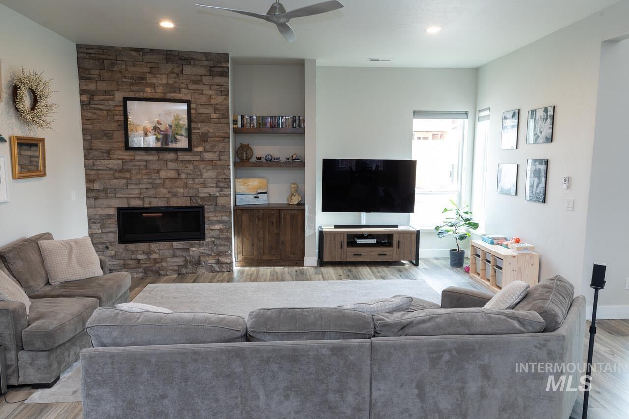 Living room featuring a fireplace, a ceiling fan, wood finished floors, built in features, and recessed lighting