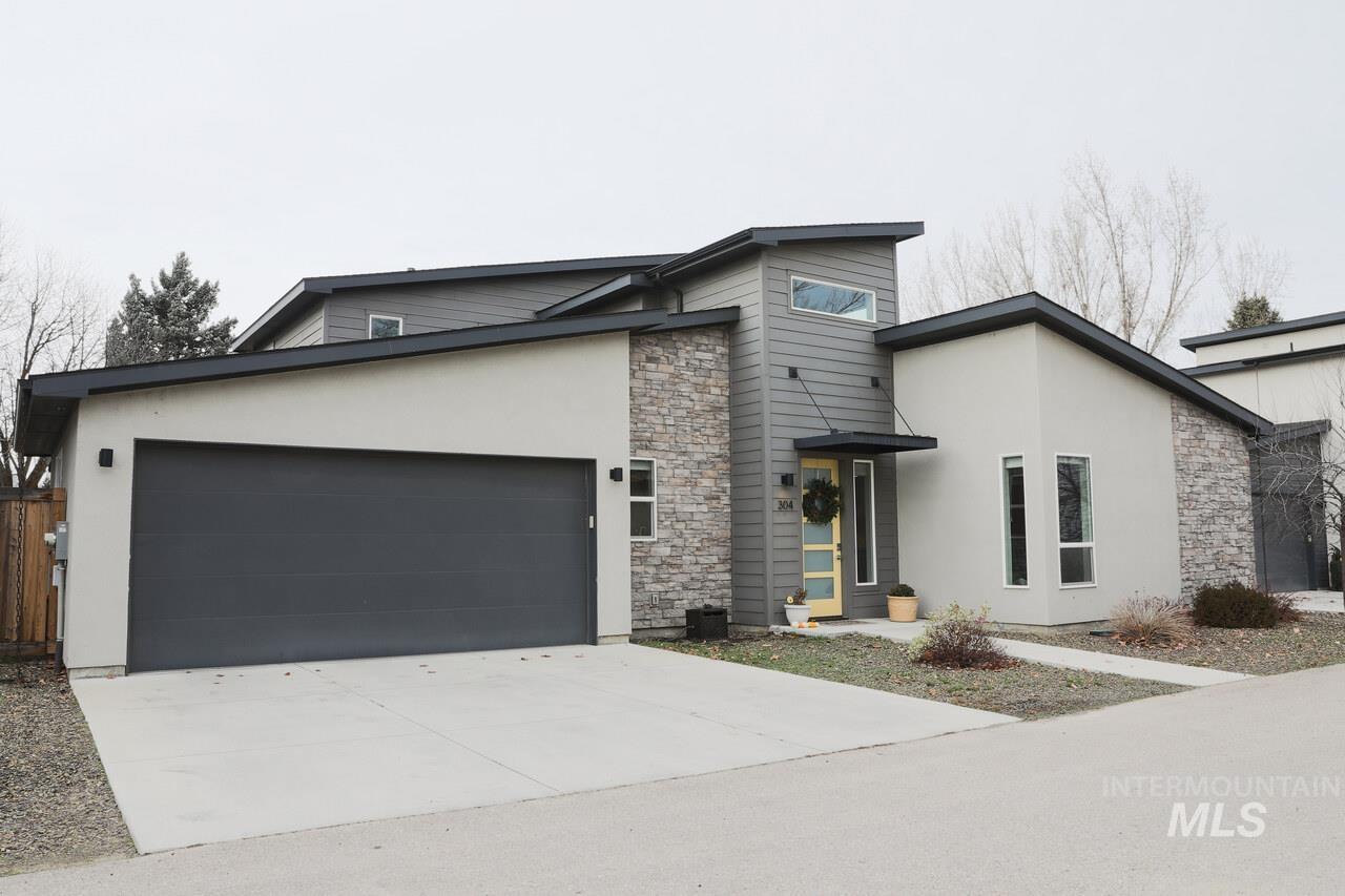 Modern home featuring stone siding, stucco siding, concrete driveway, and an attached garage