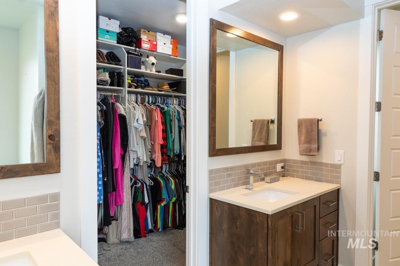 Full bathroom with vanity, tasteful backsplash, and a spacious closet
