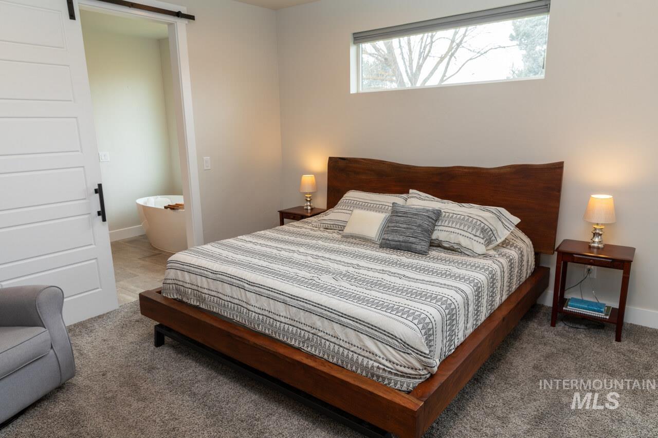 Carpeted bedroom featuring a barn door and ensuite bath
