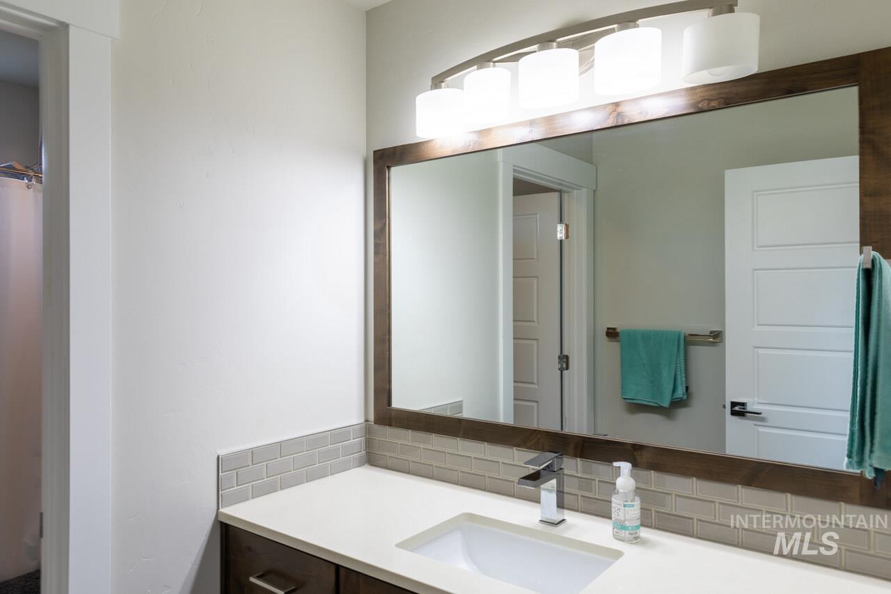 Bathroom with vanity, decorative backsplash, and a shower with shower curtain