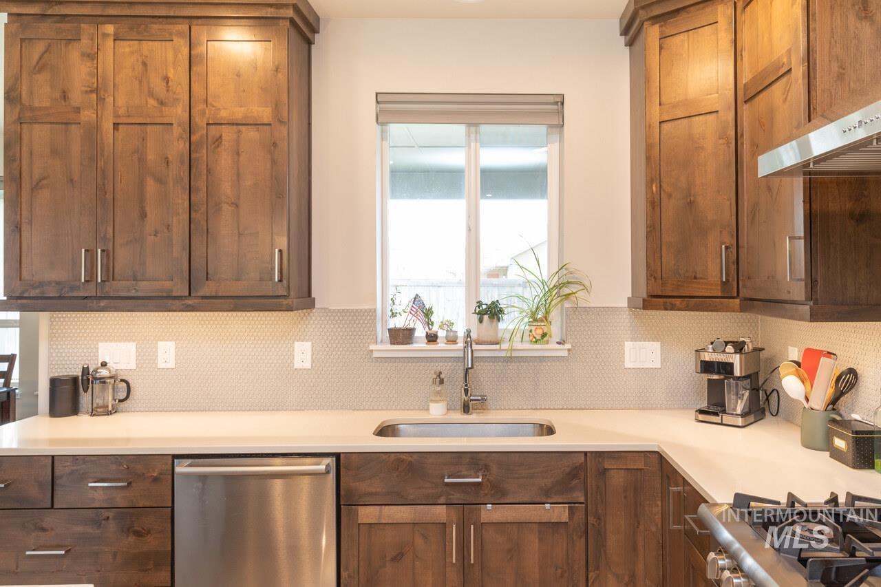 Kitchen with appliances with stainless steel finishes, healthy amount of natural light, tasteful backsplash, and light stone counters