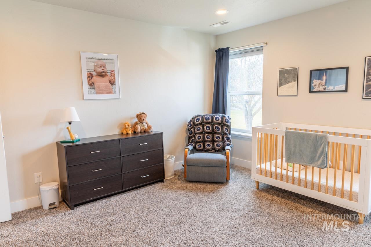 Bedroom featuring light carpet and a nursery area