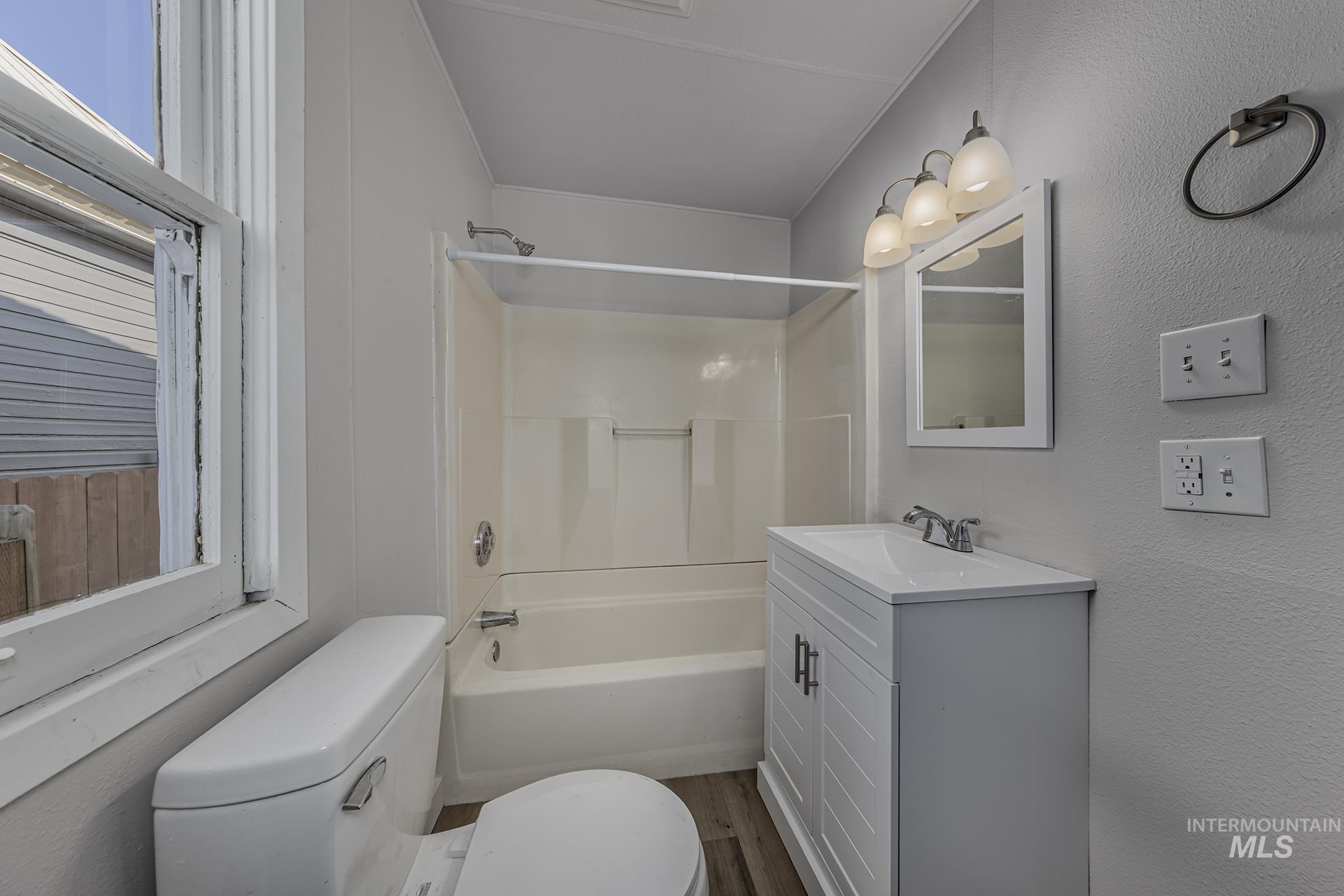 Bathroom with shower / bathtub combination, vanity, and wood finished floors