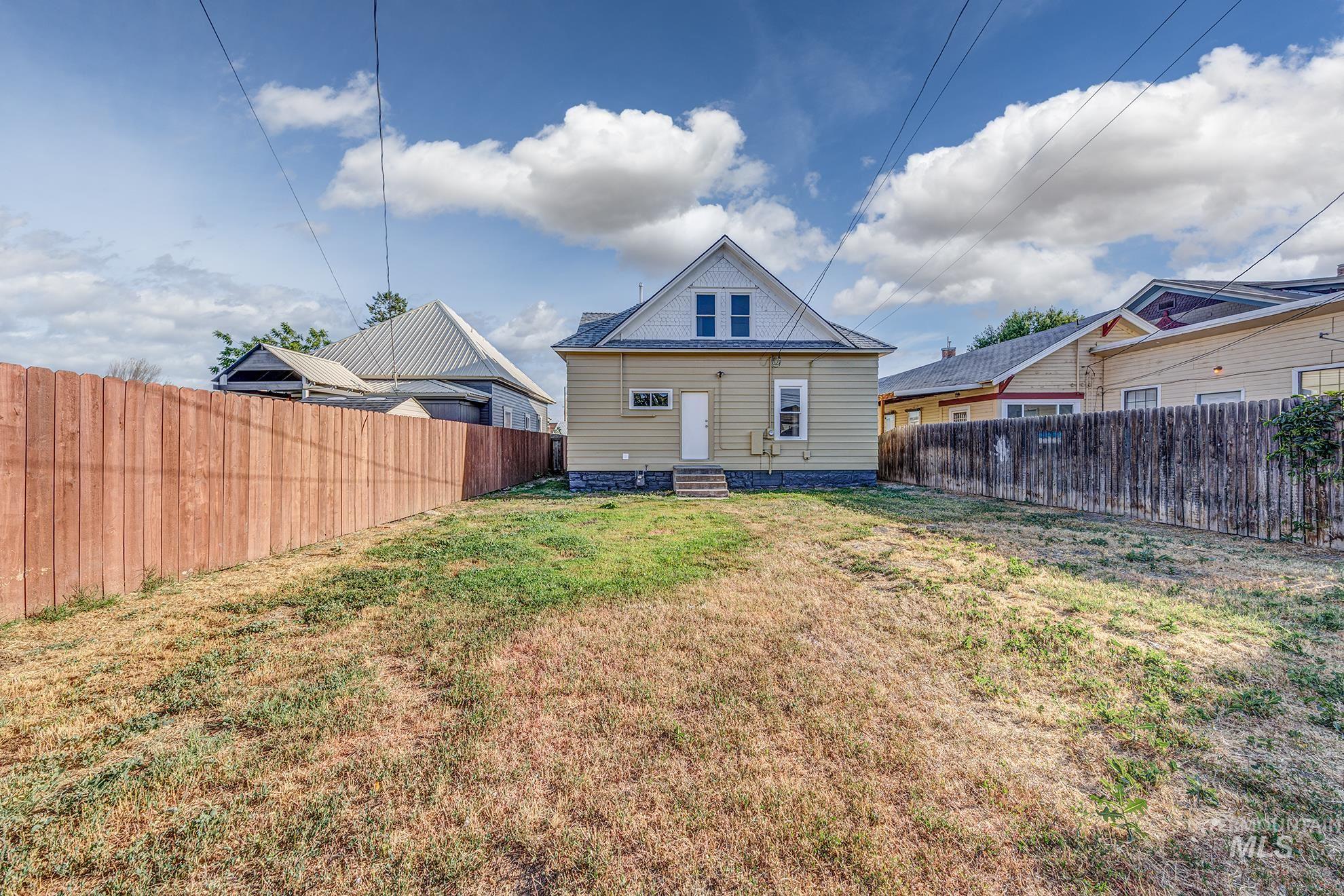 Rear view of house with entry steps and a fenced backyard