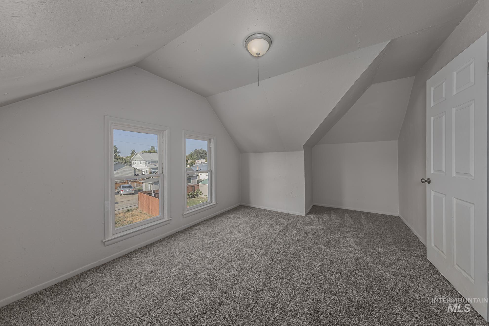 Additional living space with carpet flooring and lofted ceiling