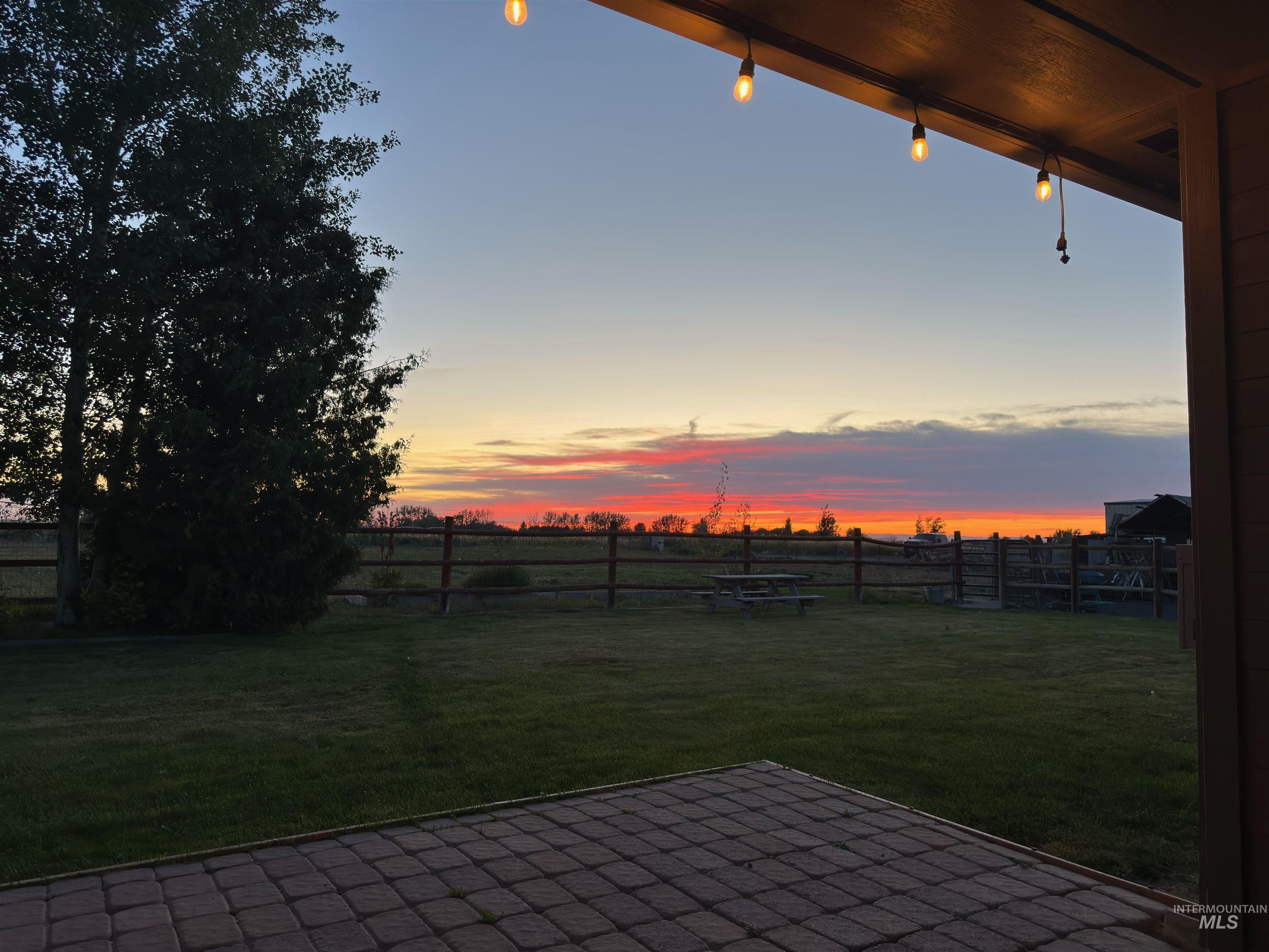Yard at dusk featuring a fenced backyard, a patio, and a view of countryside