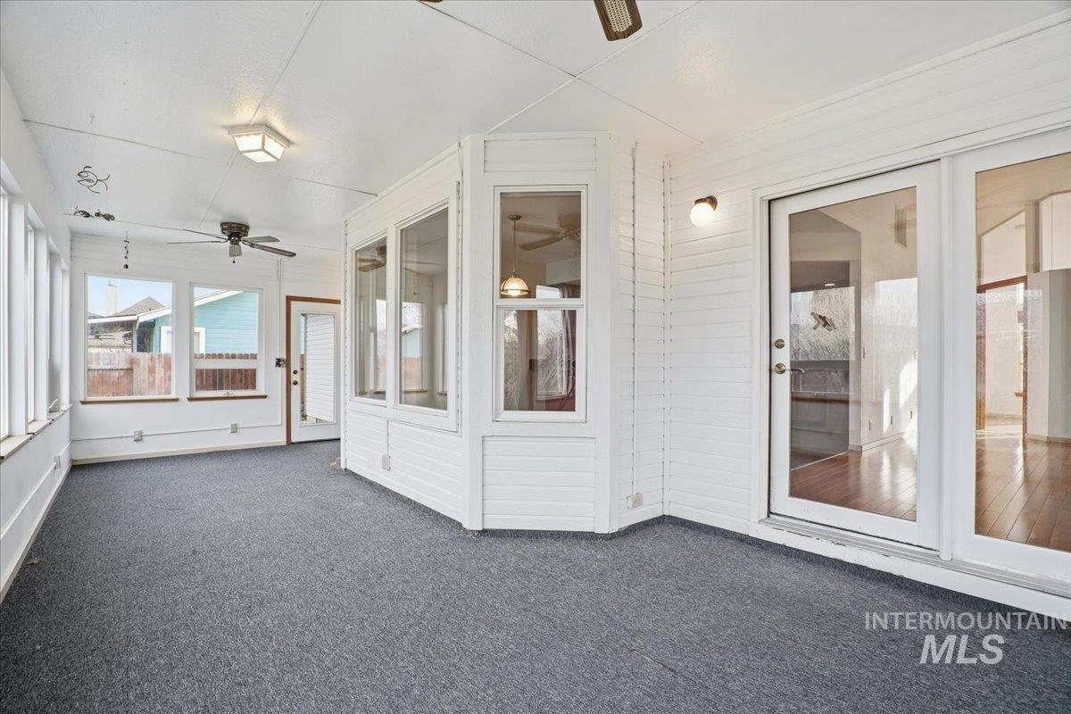 Unfurnished sunroom featuring ceiling fan