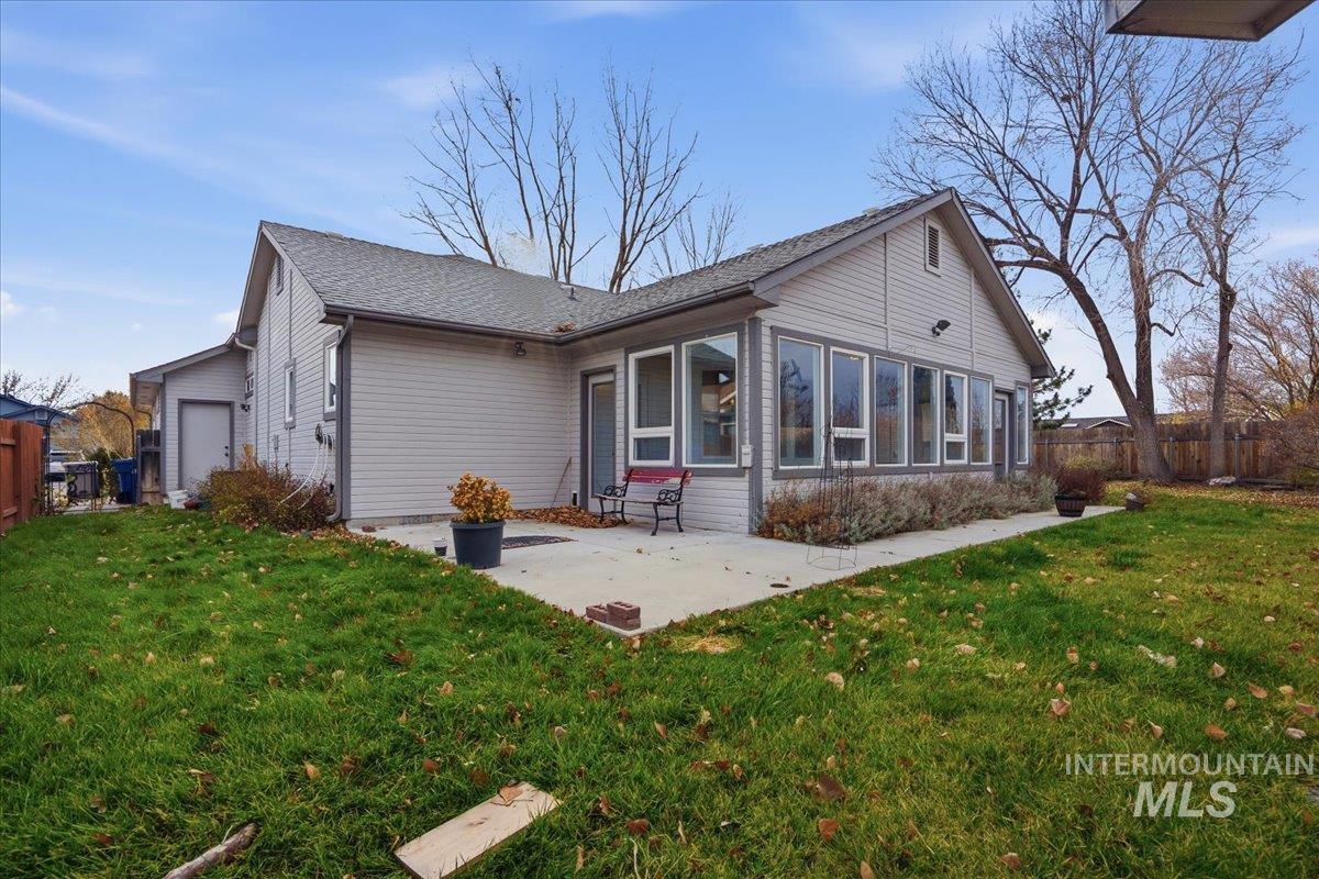 Rear view of house with a sunroom, a patio, and roof with shingles