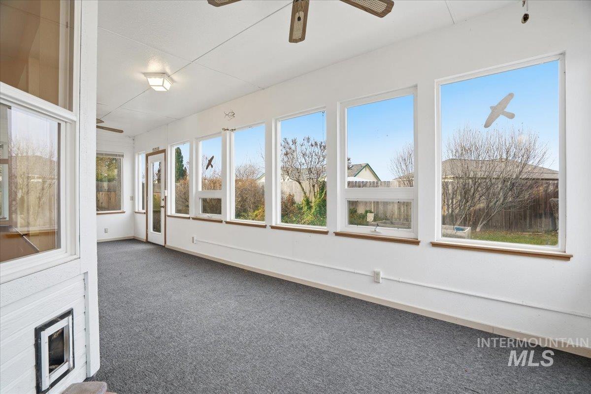 Unfurnished sunroom featuring carpet and baseboards