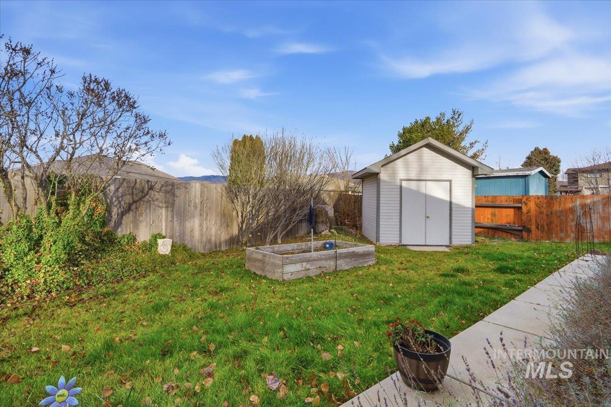 Fenced backyard featuring a garden and a shed