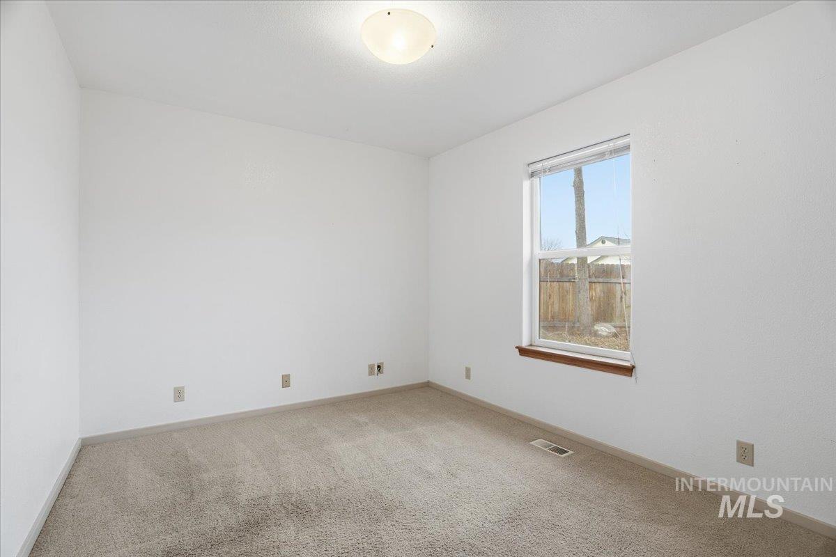Empty room featuring light colored carpet and baseboards