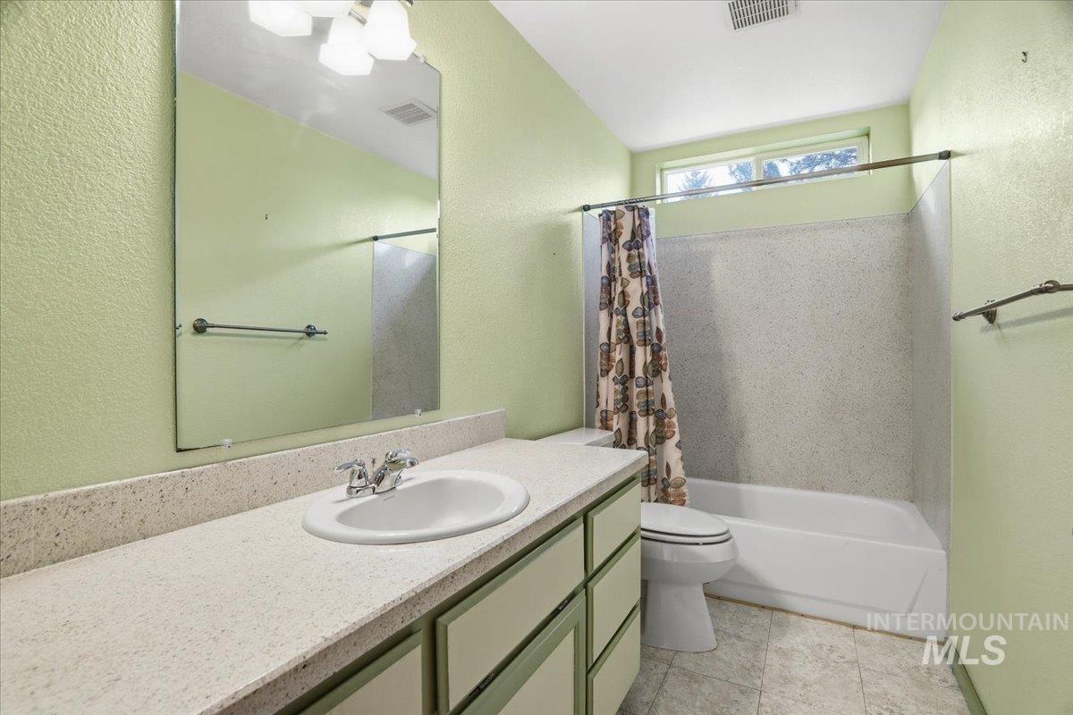 Bathroom with a textured wall, shower / tub combo, and vanity