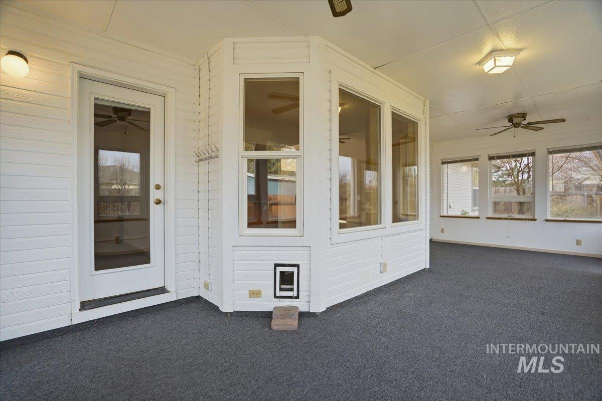 Unfurnished sunroom with a ceiling fan and a patio area