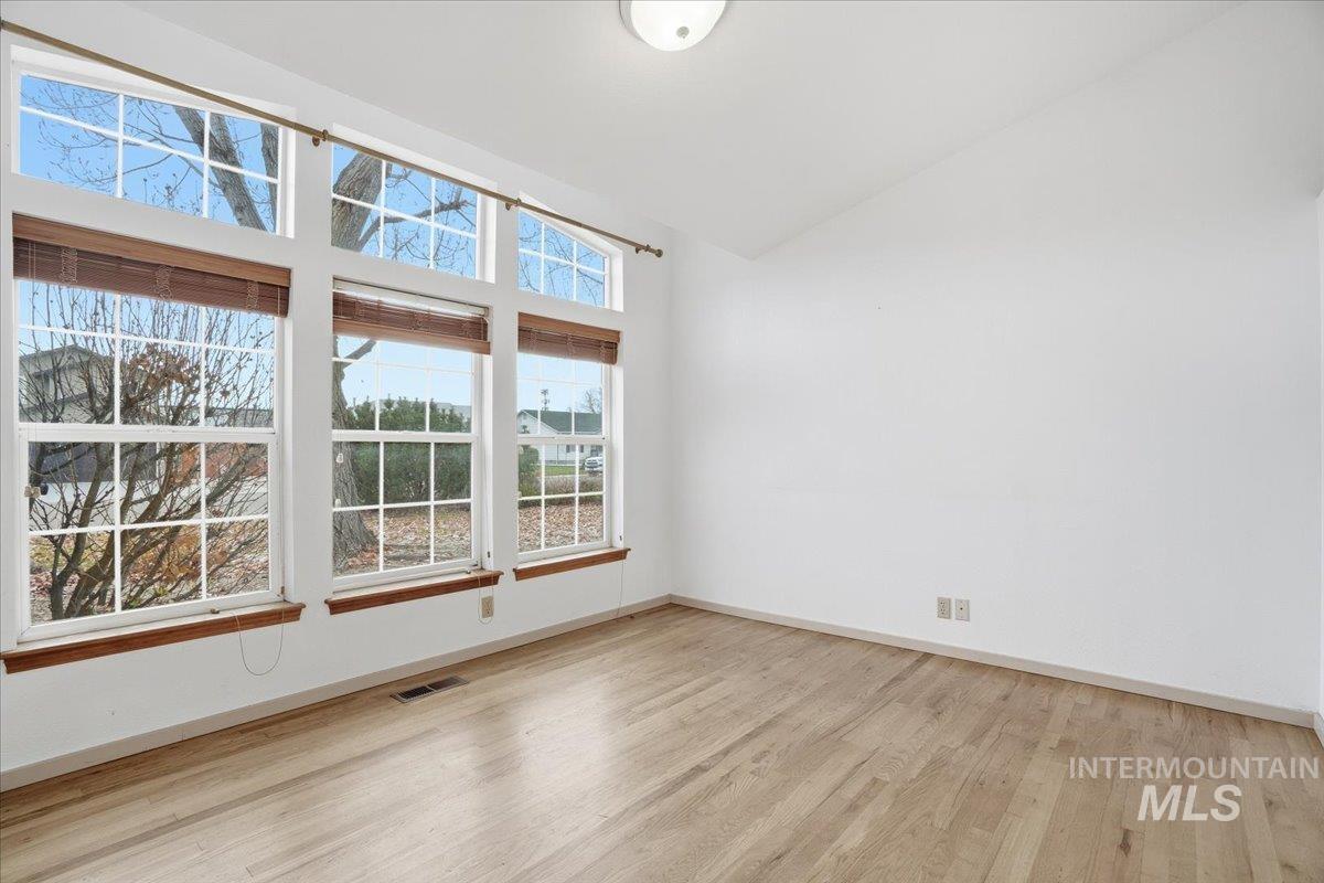 Unfurnished room featuring light wood-type flooring and high vaulted ceiling