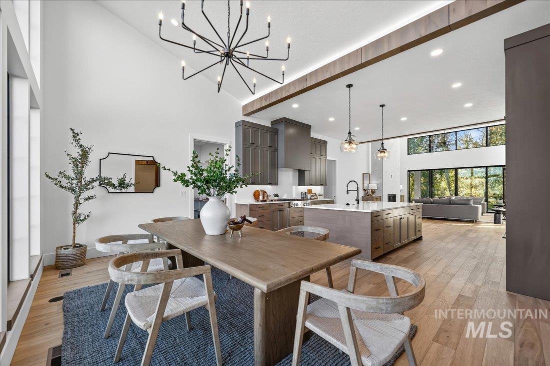 Dining area featuring a towering ceiling, light wood-style floors, recessed lighting, and a chandelier