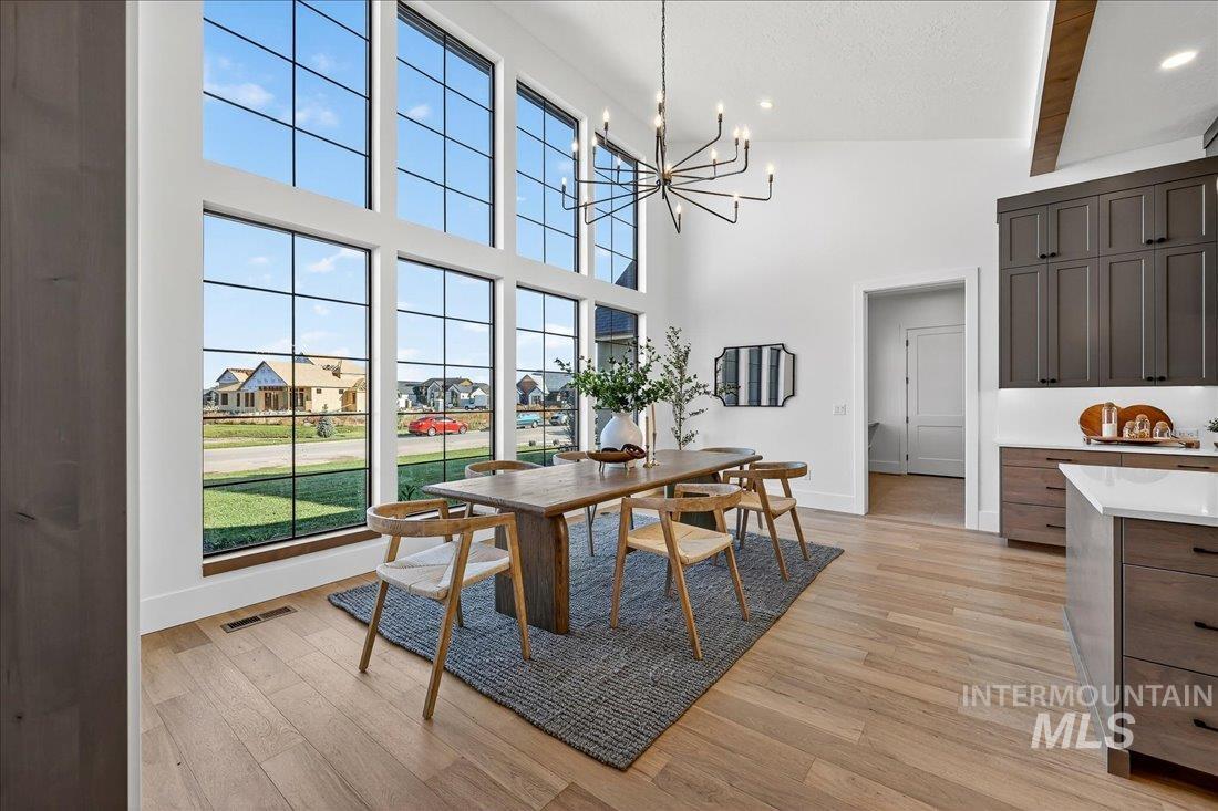 Dining room with a residential view, a chandelier, light wood-style floors, a high ceiling, and beamed ceiling