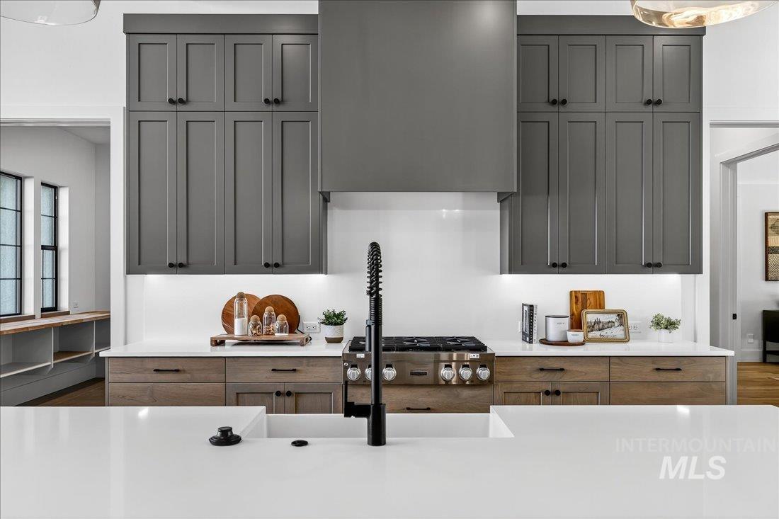 Kitchen featuring light stone countertops, gray cabinets, and ventilation hood