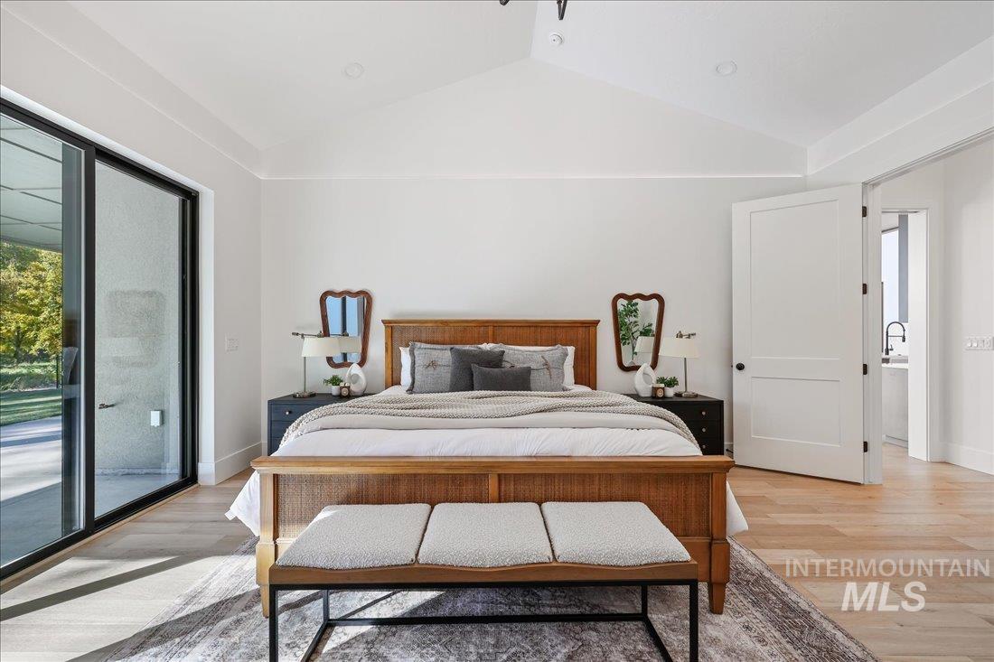 Bedroom with vaulted ceiling, wood finished floors, and access to outside