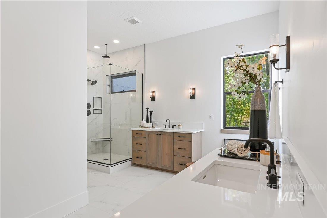 Full bathroom with two vanities, a marble finish shower, light marble finish floors, and recessed lighting
