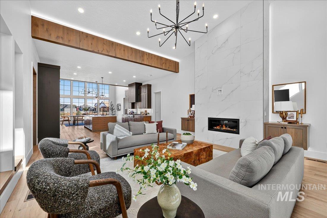 Living room with light wood-style floors, a chandelier, recessed lighting, a fireplace, and expansive windows