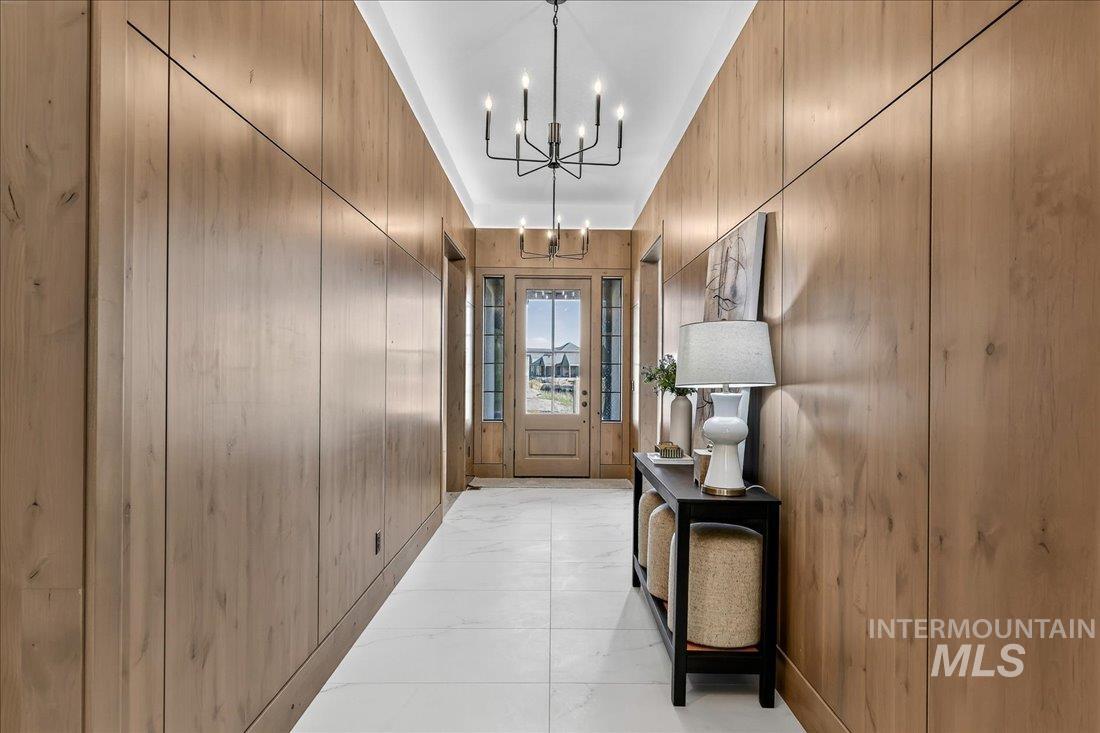 Doorway with a chandelier and wood walls