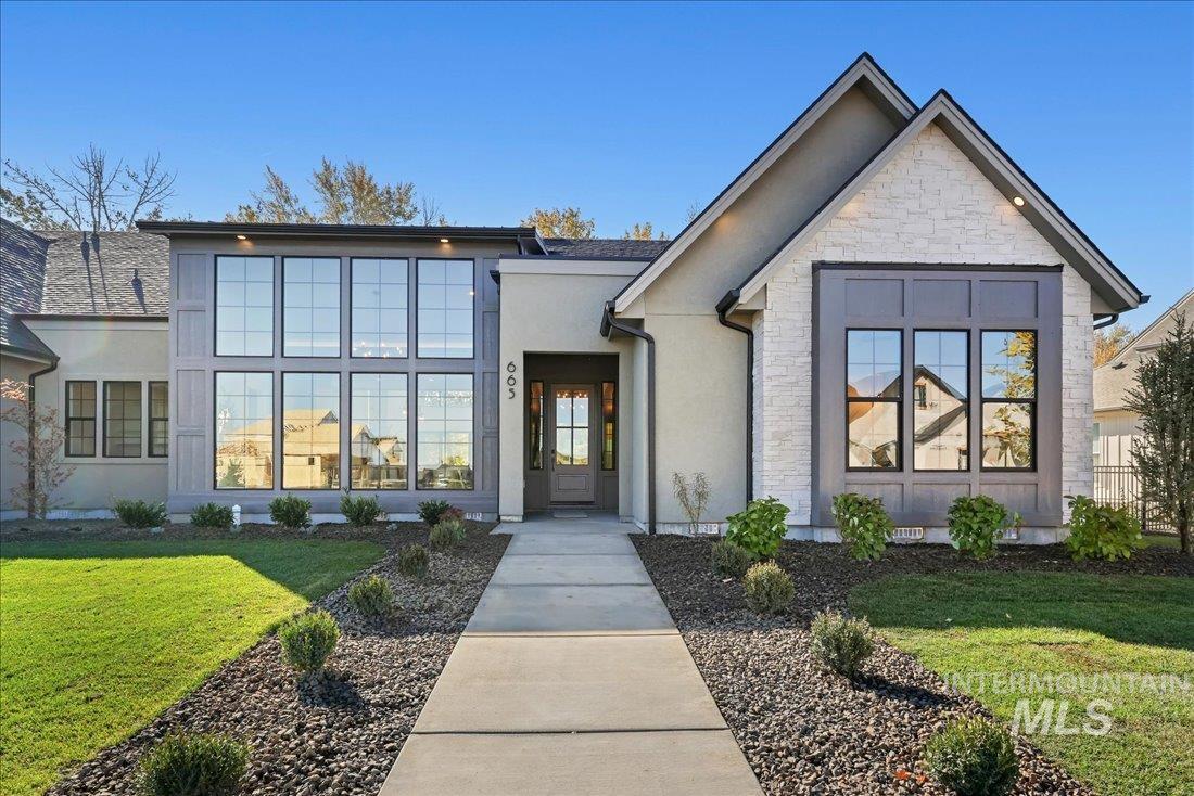 View of front of home with a front lawn, stone siding, and stucco siding
