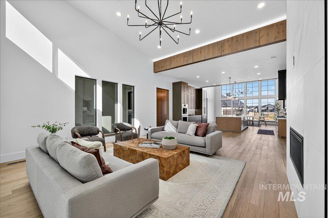 Living area featuring a chandelier, recessed lighting, a large fireplace, light wood-style flooring, and a wall of windows