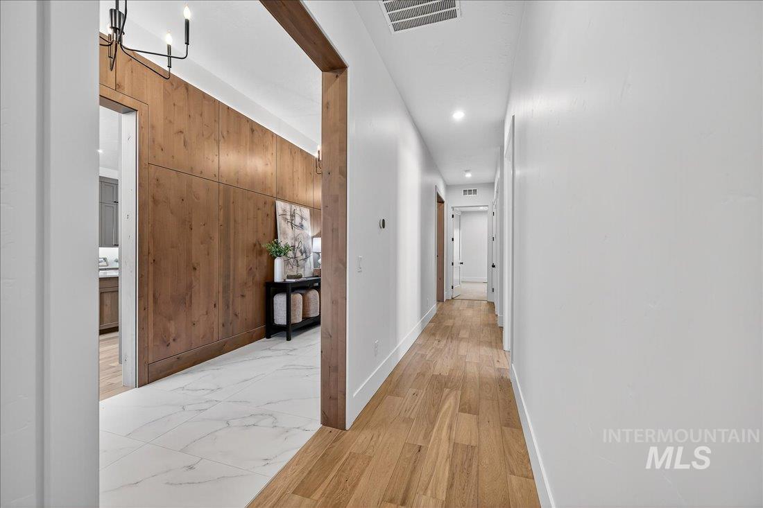 Hall with wooden walls, light wood finished floors, a chandelier, and recessed lighting