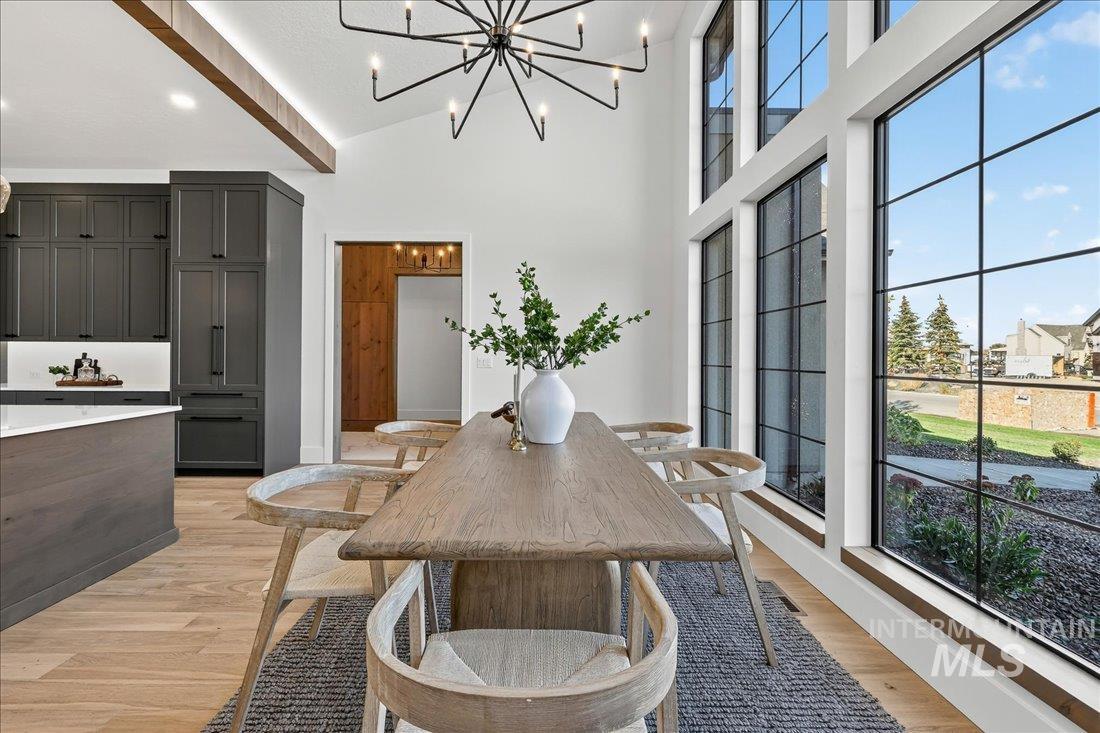 Dining area with light wood-style floors, a high ceiling, and a chandelier
