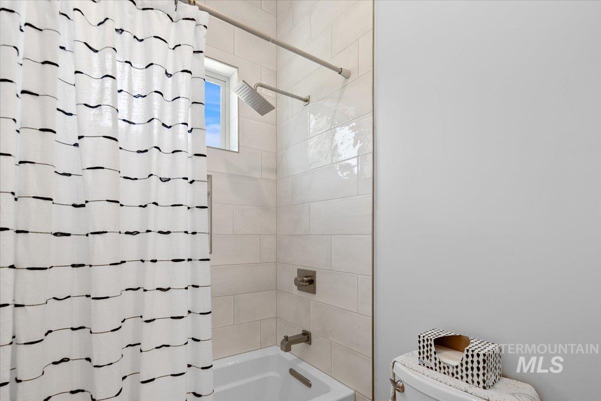 Full bathroom with toilet and shower / bathtub combination with curtain