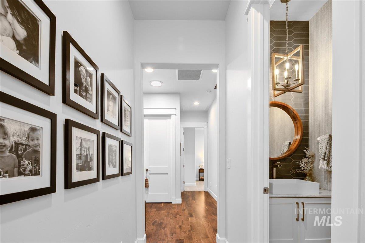 Corridor featuring dark wood-style floors and a chandelier
