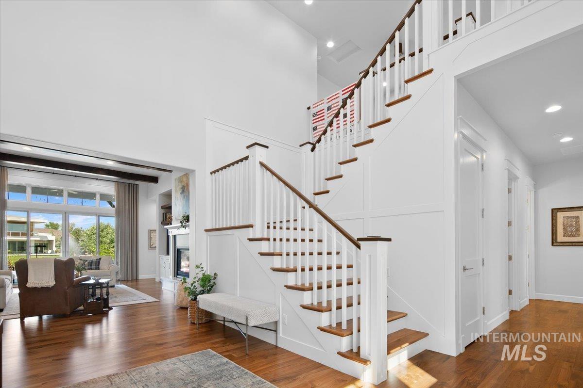 Staircase featuring recessed lighting, wood finished floors, a glass covered fireplace, and a high ceiling