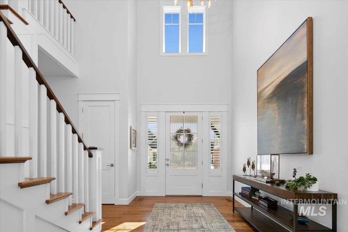 Foyer featuring plenty of natural light, stairs, wood finished floors, and a towering ceiling