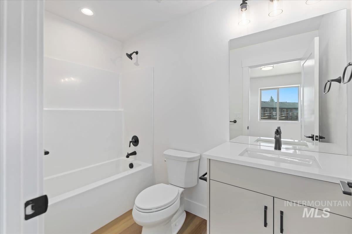 Bathroom with vanity, bathing tub / shower combination, light wood-style flooring, and recessed lighting