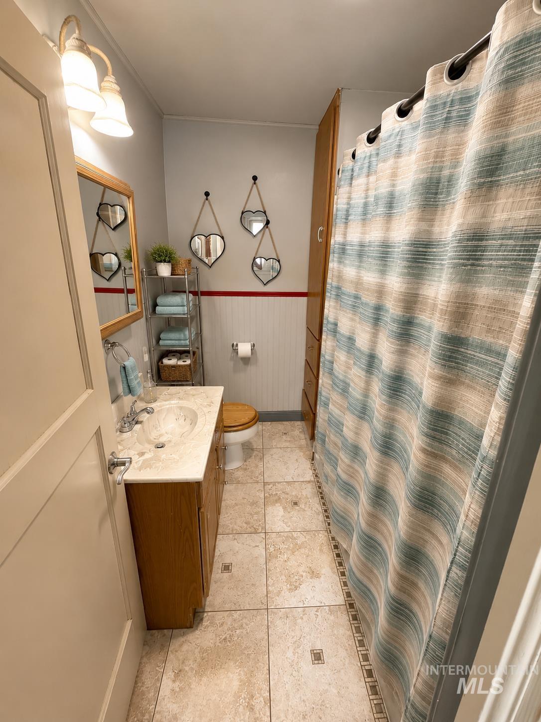 Bathroom featuring a wood vanity with an integrated sink, polished chrome faucet, and a wall-mounted light fixture