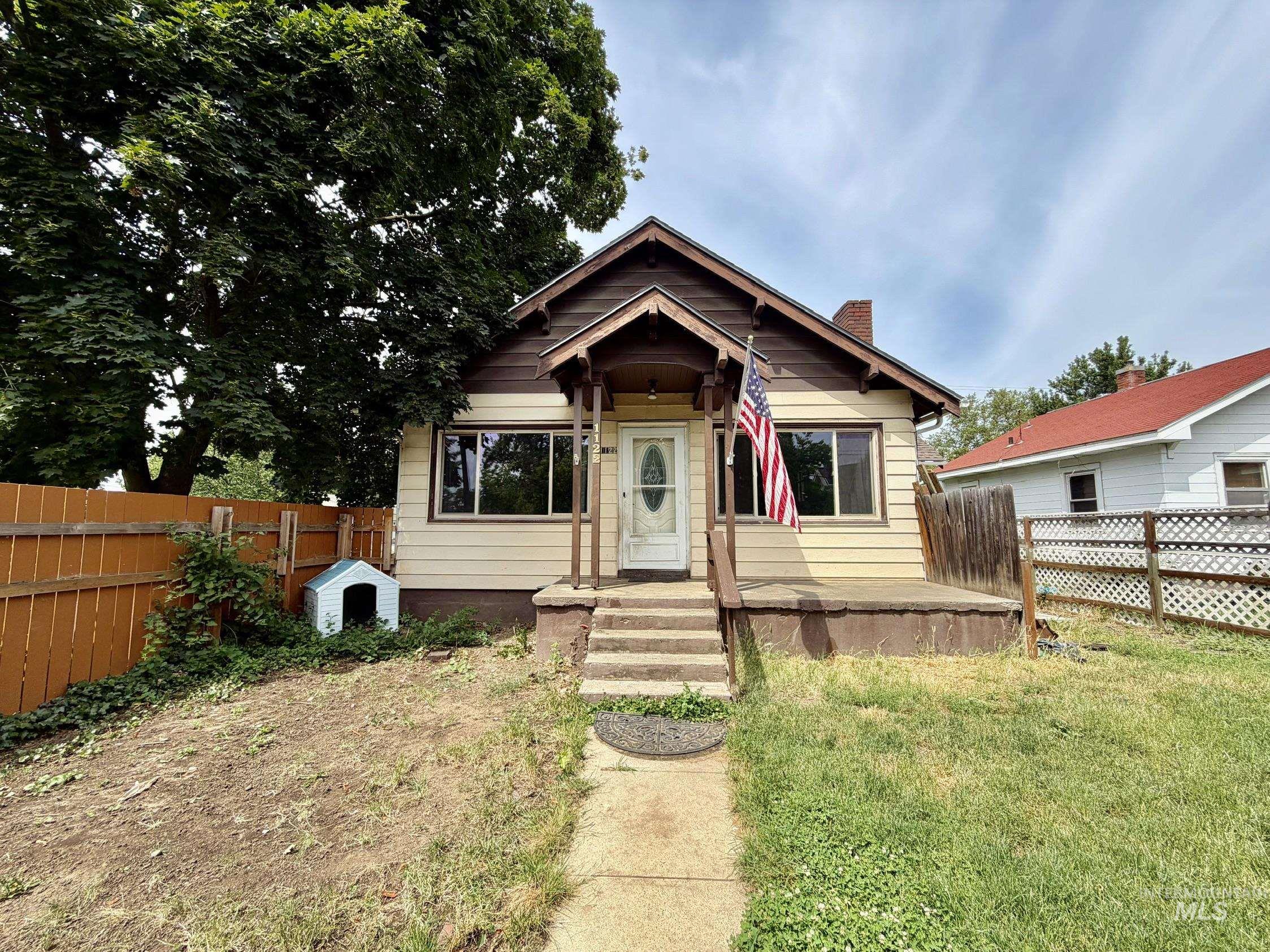 Exterior features include light-colored siding with brown trim accents, a covered front porch, and a white front door with decorative glass
