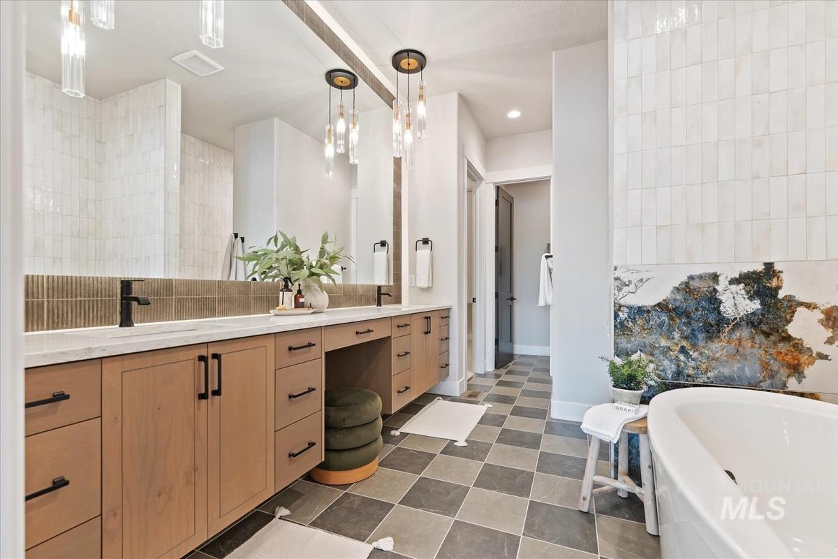 Bathroom with double vanity, a tub to relax in, and dark flooring