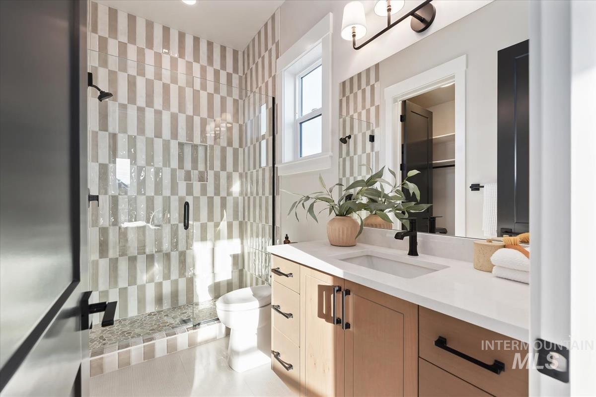 Full bath featuring vanity, a stall shower, and a walk in closet