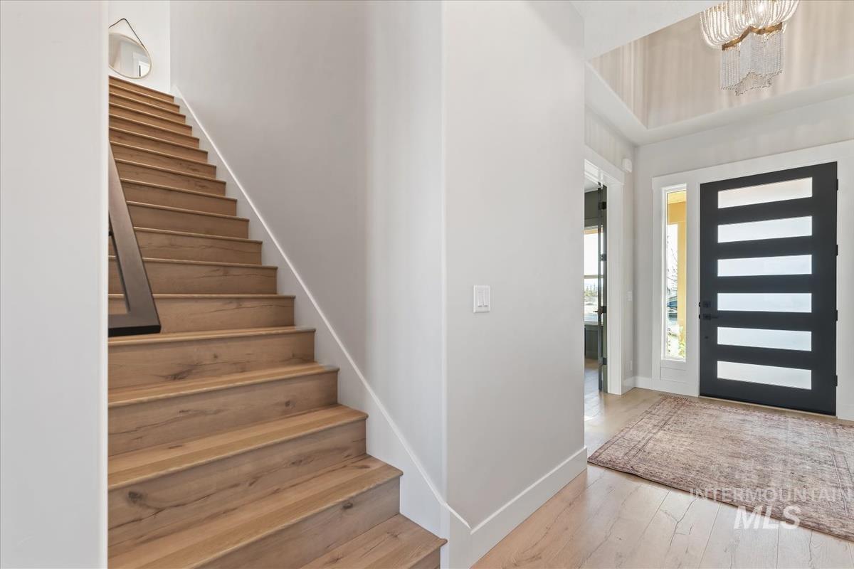 Foyer entrance featuring stairs, light wood finished floors, and a chandelier