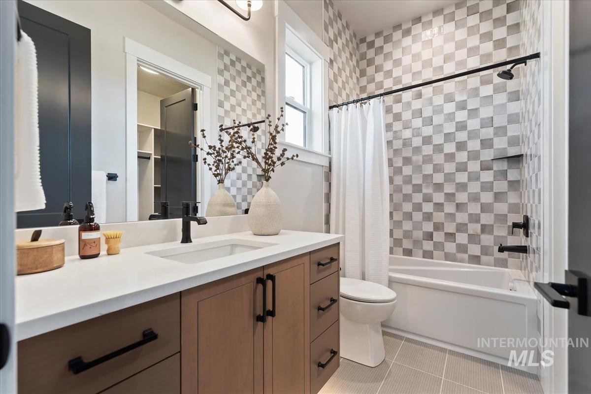 Full bathroom featuring shower / bathtub combination with curtain, vanity, and light tile patterned flooring