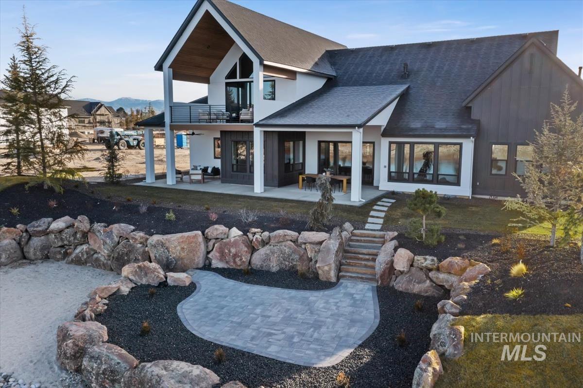 Rear view of house featuring a patio area, roof with shingles, and a balcony
