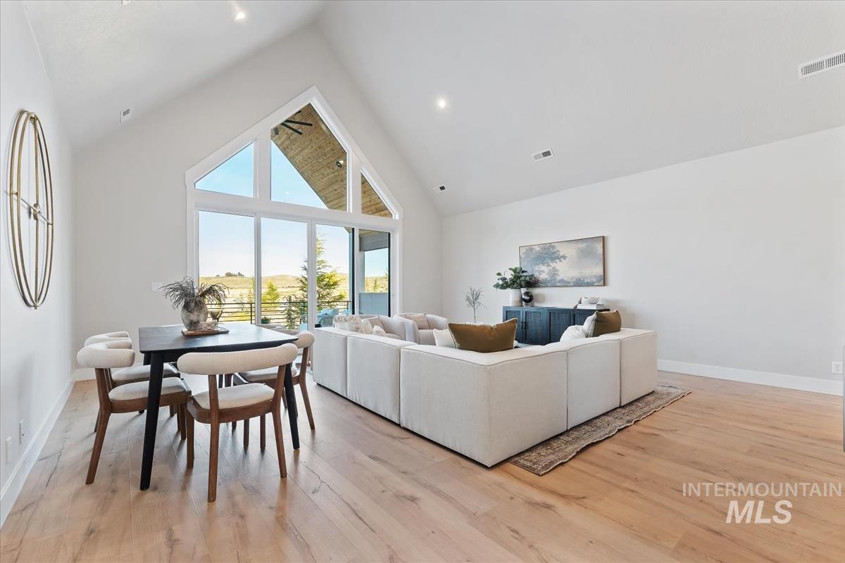 Living area with high vaulted ceiling and light wood-type flooring