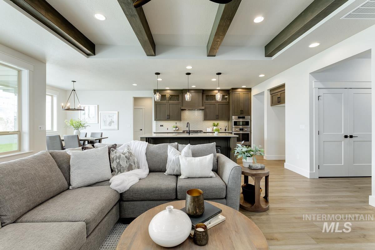 Living area with recessed lighting, light wood finished floors, beamed ceiling, and a chandelier