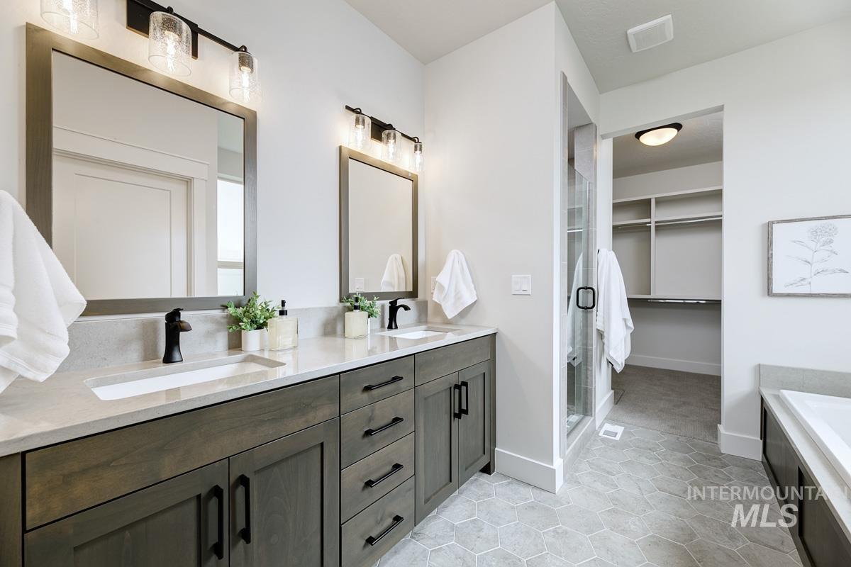 Bathroom featuring double vanity, a spacious closet, light tile patterned floors, a bath, and a stall shower