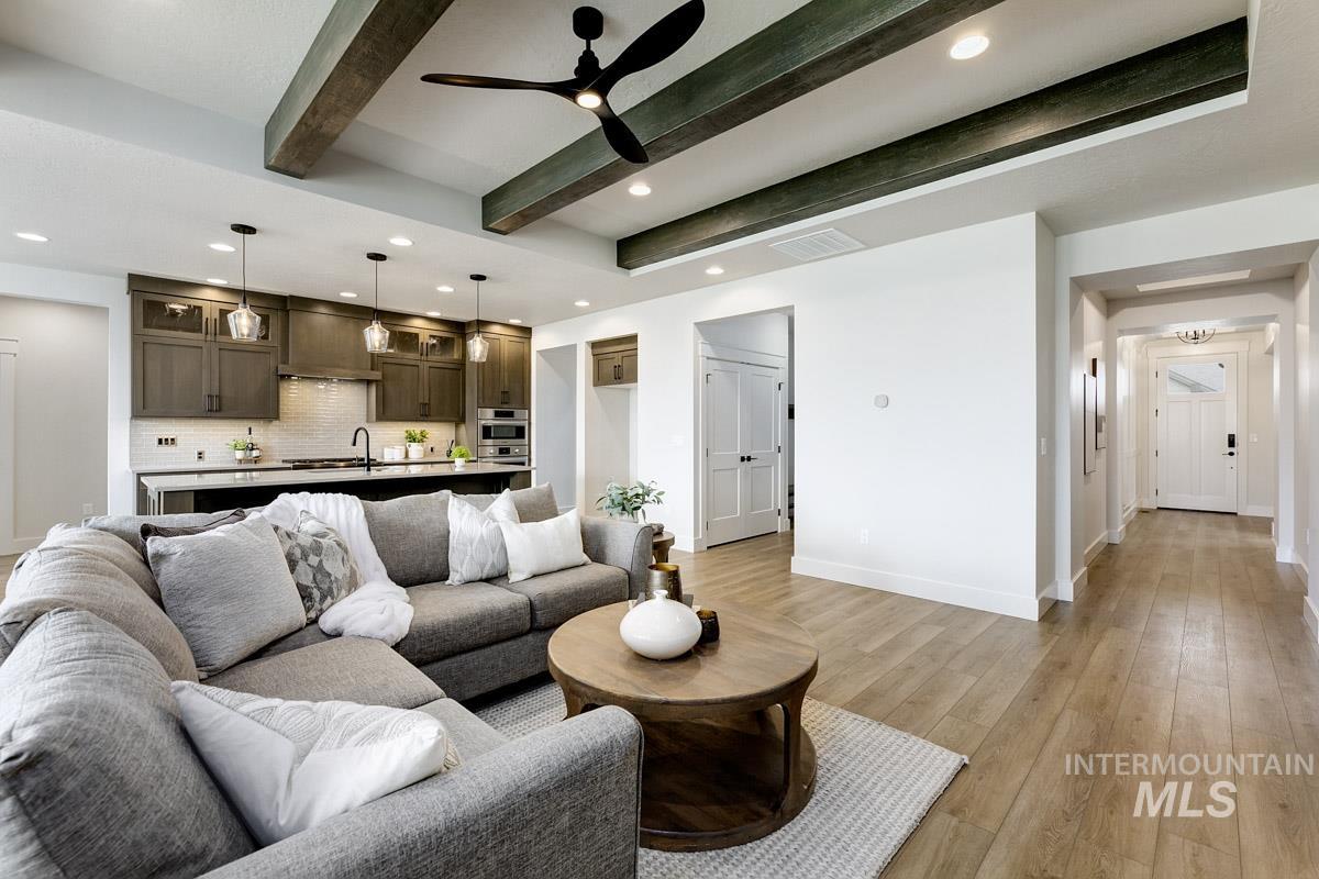 Living room featuring beamed ceiling, light wood-type flooring, ceiling fan, and recessed lighting