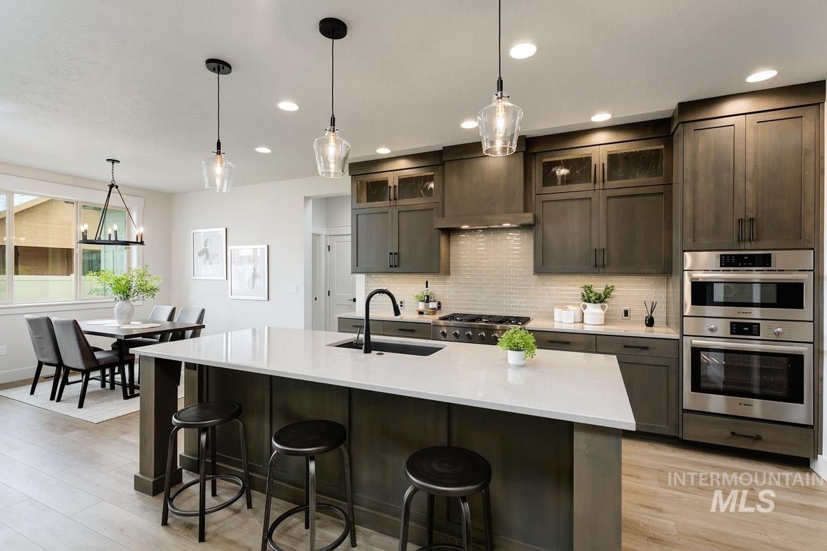Kitchen featuring pendant lighting, glass insert cabinets, backsplash, a breakfast bar, and recessed lighting