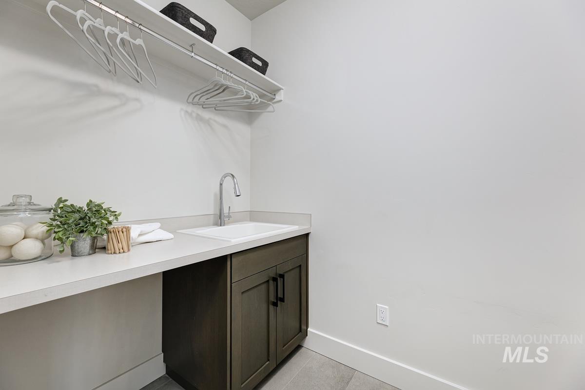 Laundry room featuring light tile patterned floors and baseboards