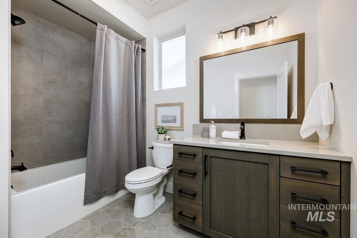 Bathroom featuring shower / bath combination with curtain, vanity, and light tile patterned flooring